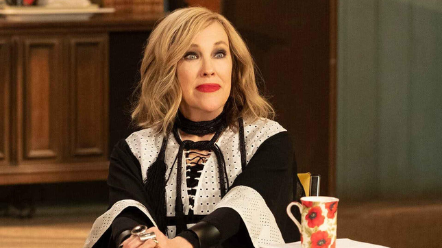 Catherine O'Hara sits at a table in Schitt's Creek